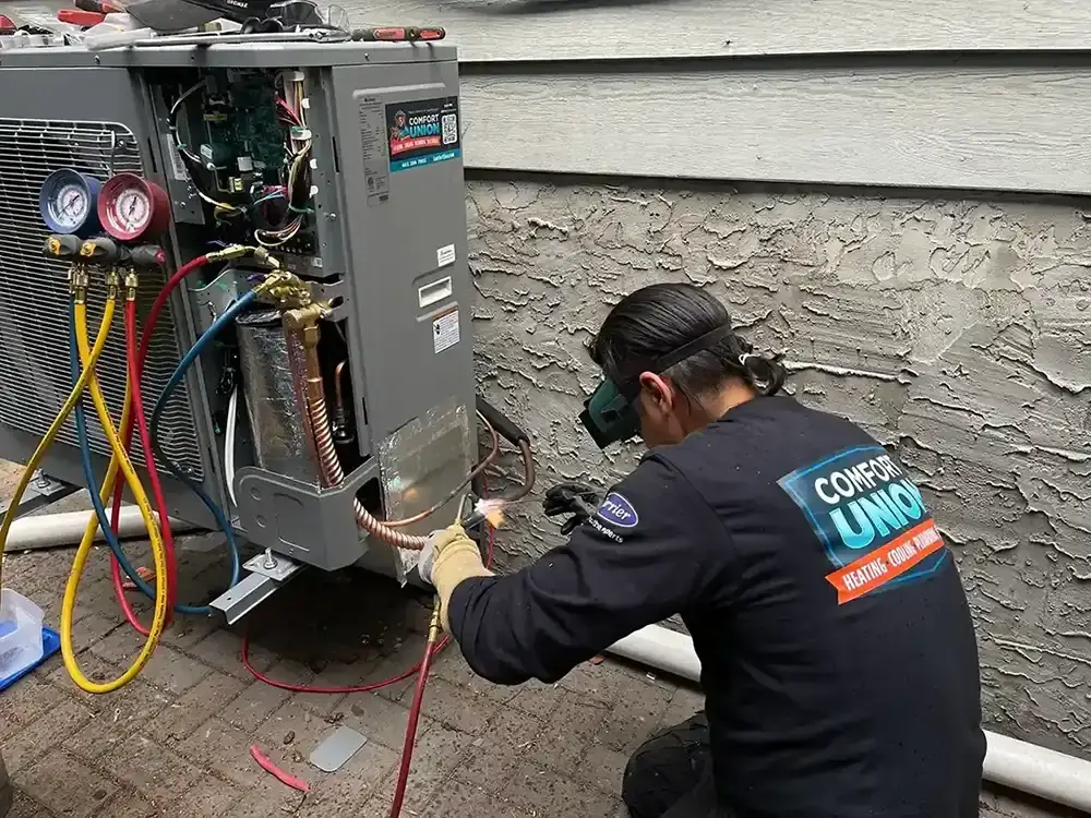 Comfort Union technician performing maintenance on an outdoor HVAC unit at a residential property